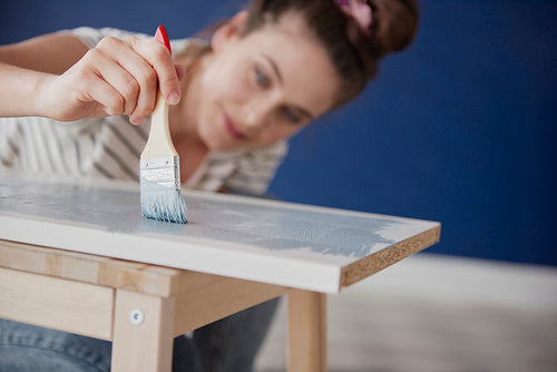 Close up of young woman repainting old furniture