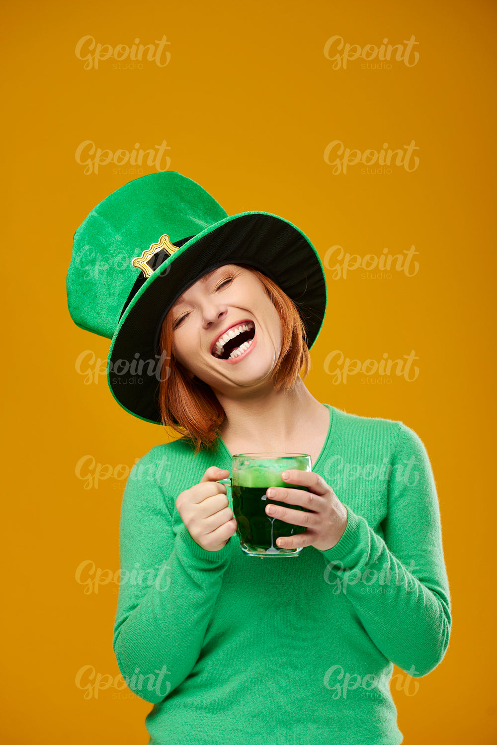 Happy woman with leprechaun's hat drinking beer