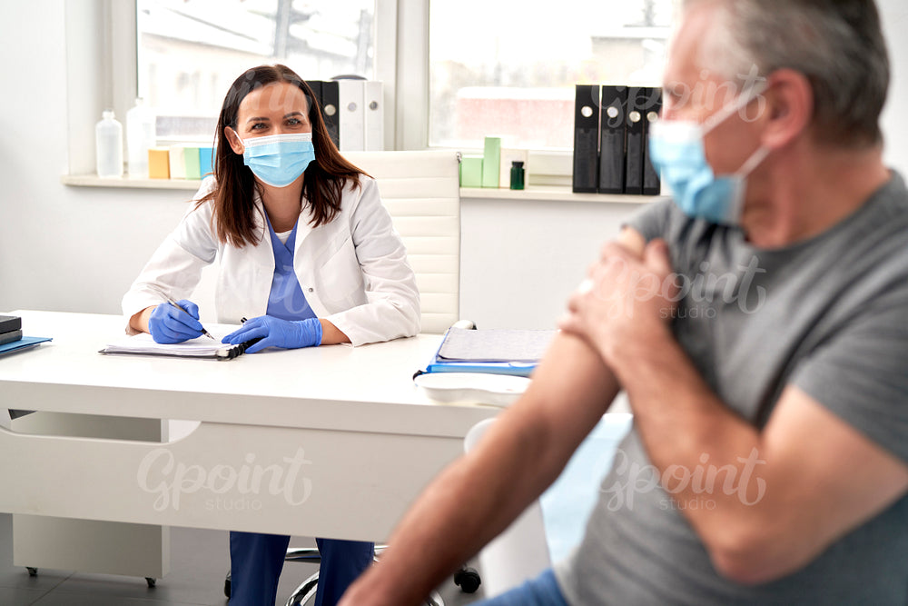 Female doctor talking to senior after vaccination
