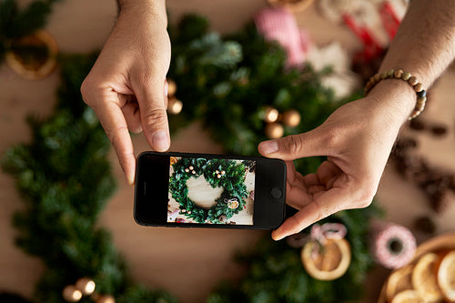 Top view of hands taking photos of the Christmas wreath