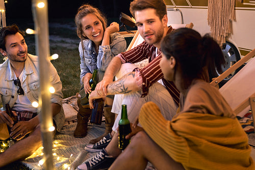 Group of young friends spending time on the camping side, drinking beer and chatting