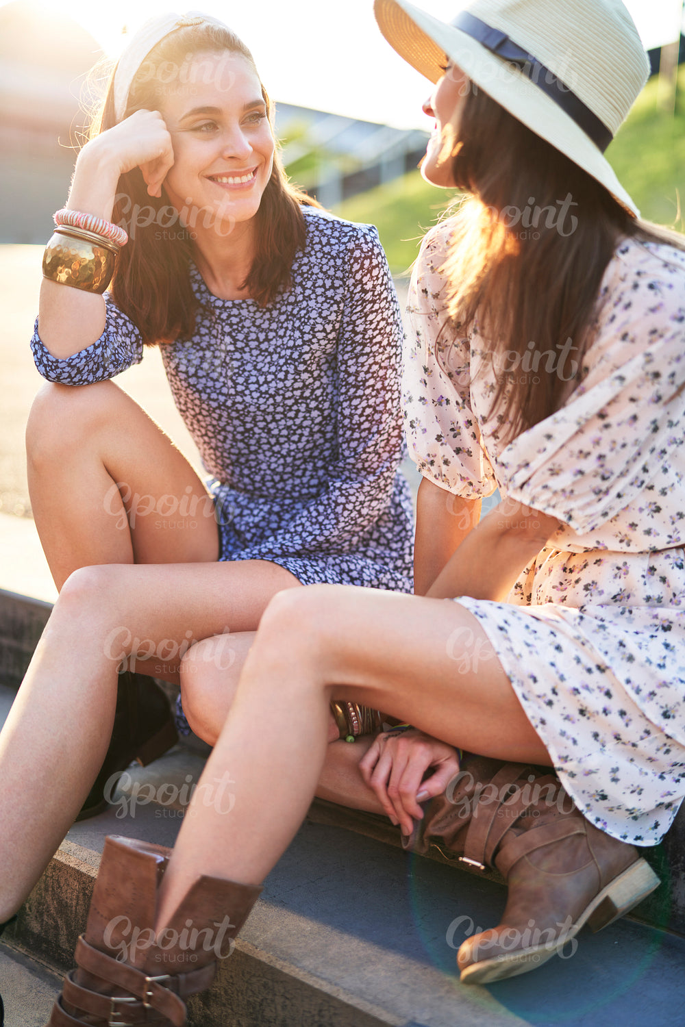 Two smiling beautiful women sitting in the sunlight