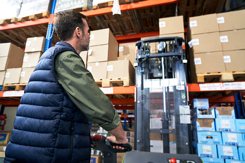 Adult caucasian man working at forklift in warehouse