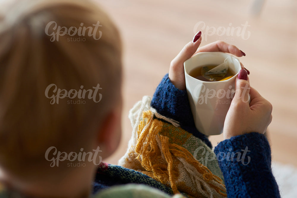 Woman's hand holding a mug of tea with lemon