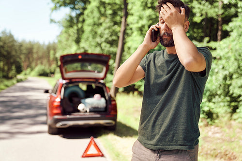 Man with car problems in forest using a mobile phone