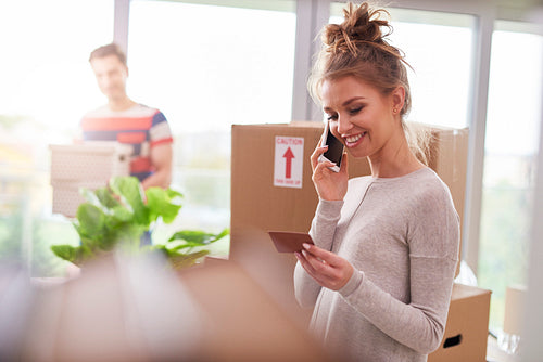 Woman using phone while moving house