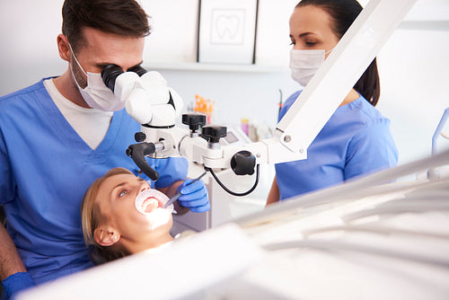 Male dentist looking through dental microscope