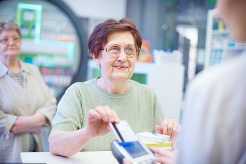 Senior woman paying with credit card in pharmacy