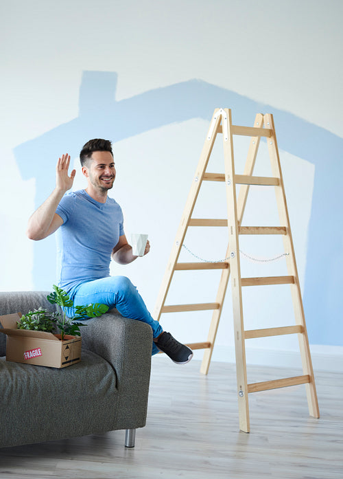 Smiling man holding moving box of plants in new home