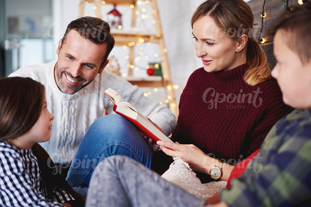 Happy family reading a book in christmas time