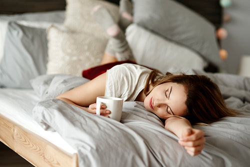 Woman with coffee reclining in bed