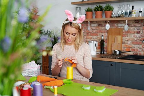 Beautiful woman in a rabbit's ears sews Easter decorations
