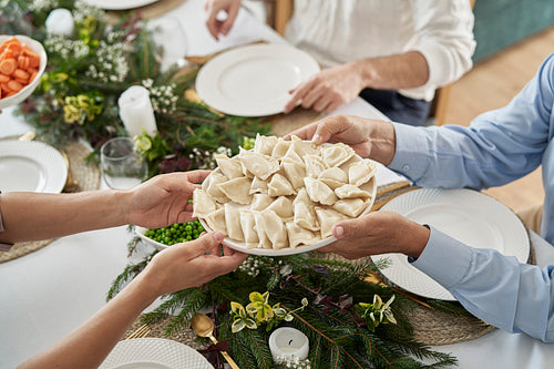 Unrecognizable people sharing a plate with traditional Polish dumplings