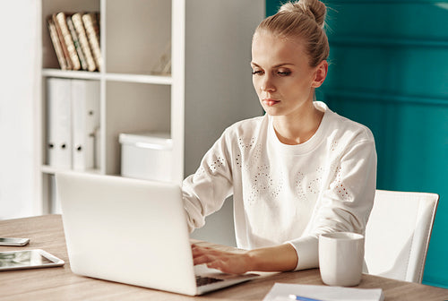 Serious woman with laptop working at home office