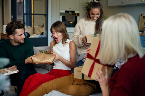Group of friends opening Christmas gifts at home