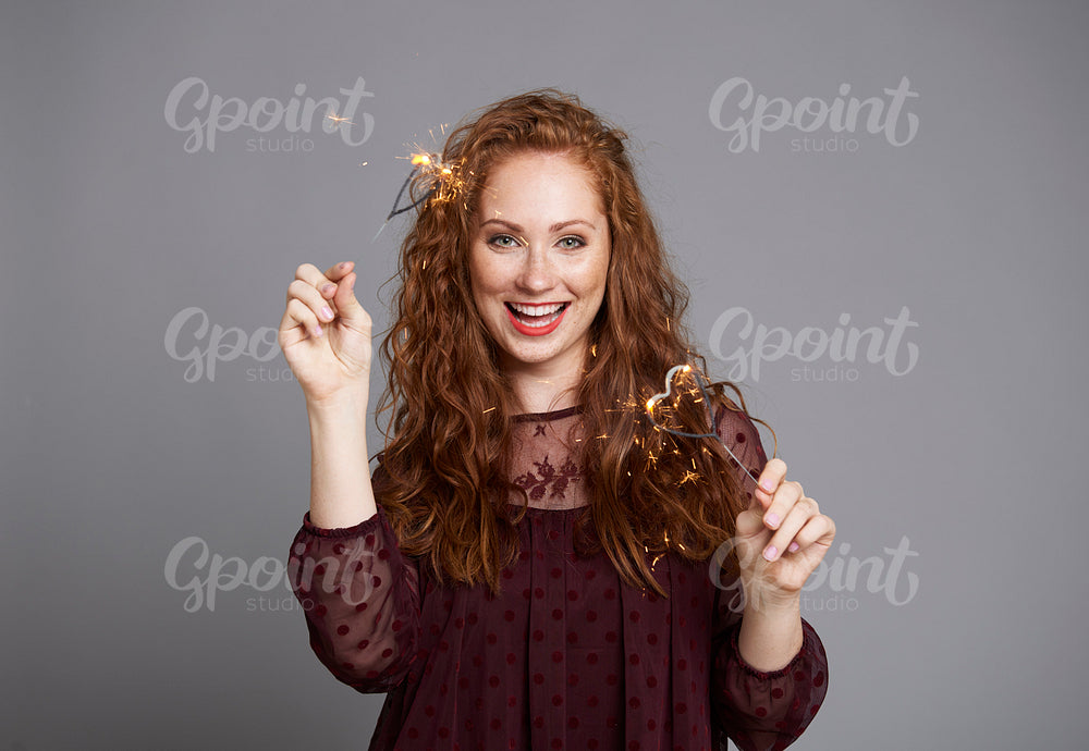 Portrait of happy woman with burning sparklers at studio shot