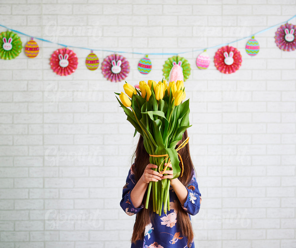 Girl holding bunch of tulips in front of her face