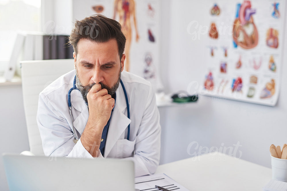 Busy doctor working with laptop in doctor’s office