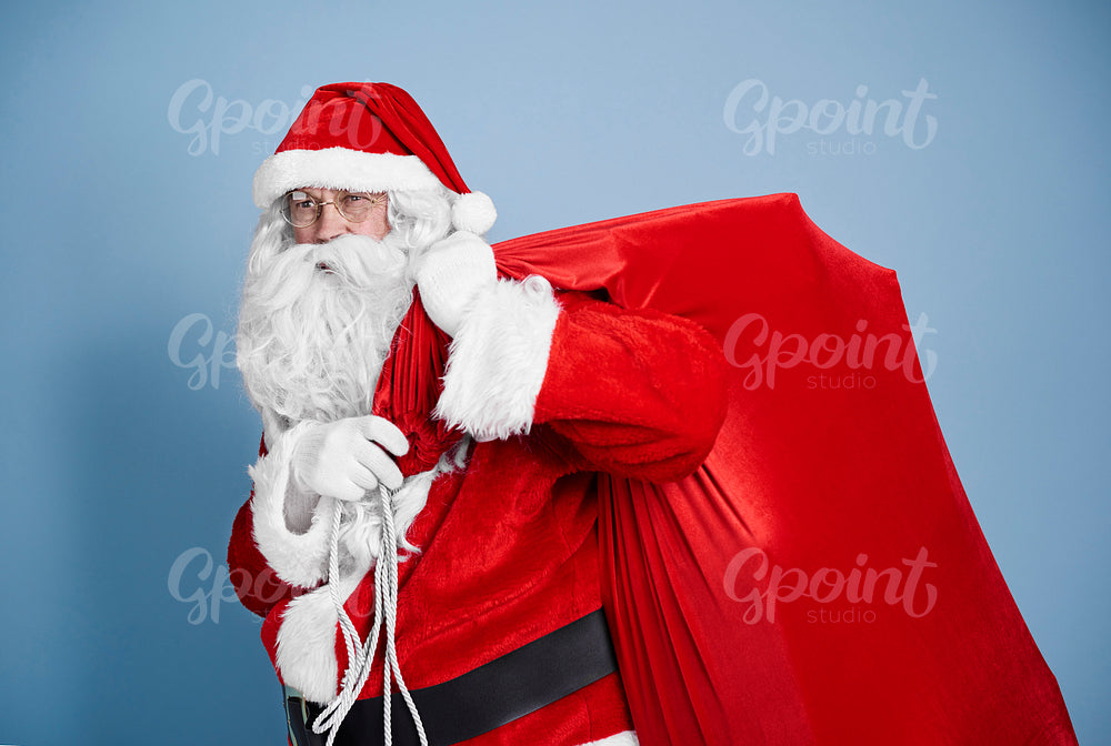 Tired santa claus carrying heavy sack