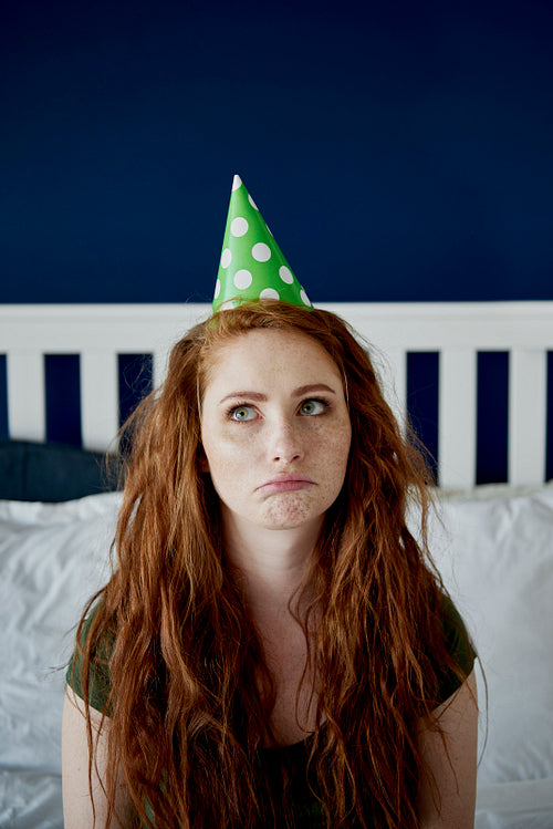 Confused redhead woman with party hat