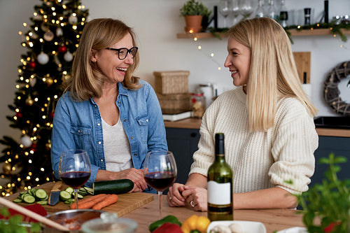 Happy two women in the kitchen with glasses of wine