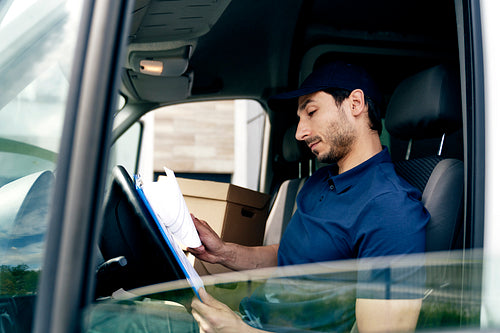 Courier looking at documents while sitting in the car