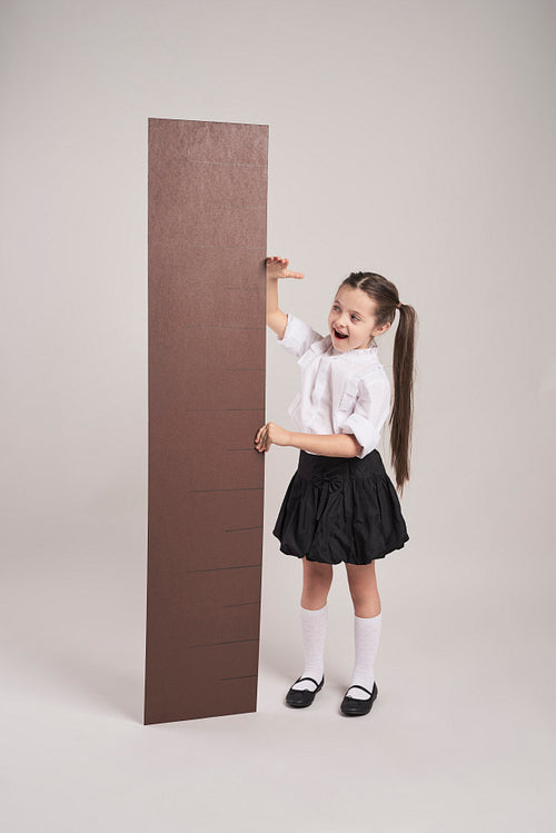 Happy girl measuring her height