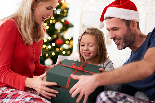 Family starting Christmas from opening gifts in bed