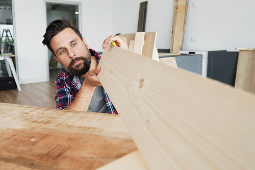 Carpenter looking at a wooden plank