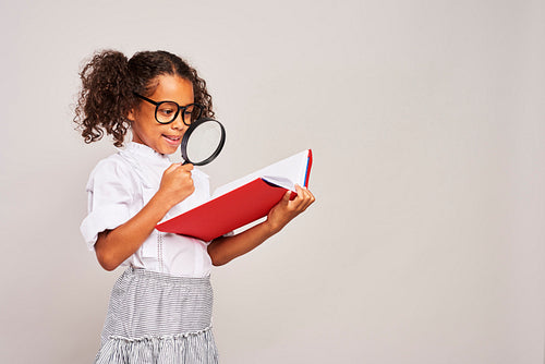 Girl holding big book and magnifying glass