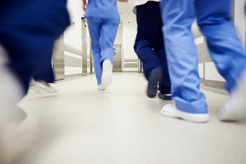 Part of doctors running through corridor in hospital