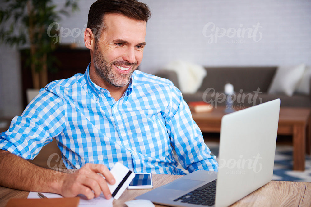 Happy man using laptop and credit card during online shopping
