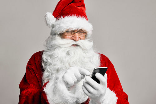 Caucasian Santa Claus in studio shot using mobile phone