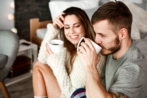 Cheerful man and woman drinking coffee in bedroom