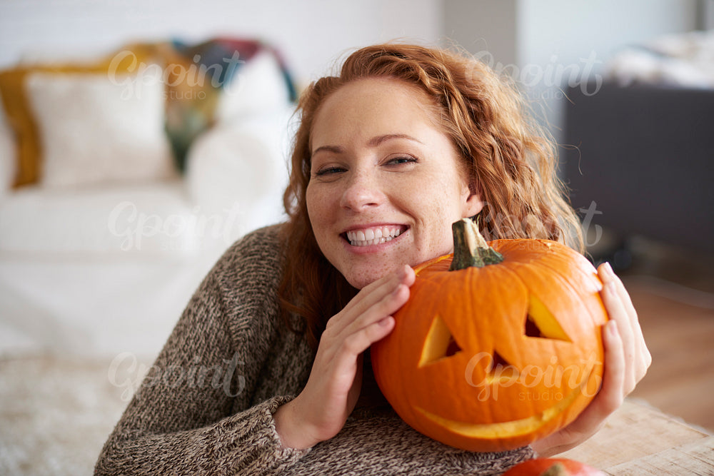 Smiling woman embracing halloween pumpkin