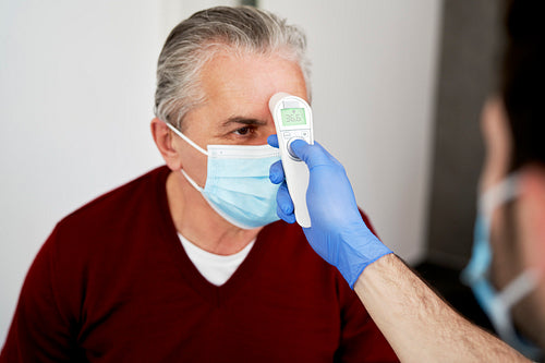 Close up of doctor measuring the temperature of the senior