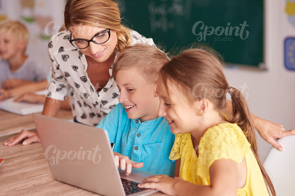 Teacher with students using laptop in classroom
