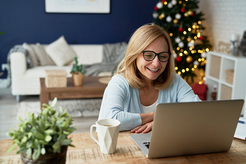 Happy mature woman having video conference during Christmas at home