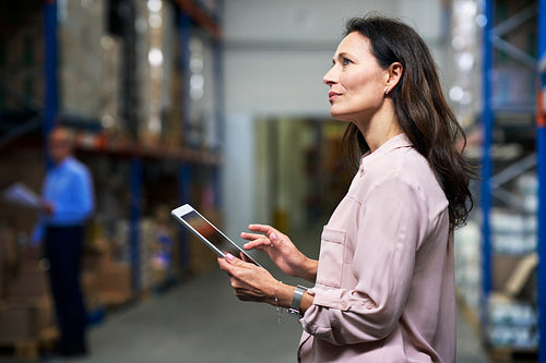 Caucasian woman working in the warehouse and holding digital tablet