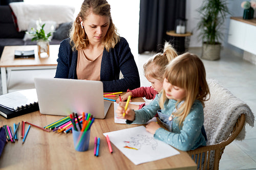 Busy mother working at home with her daughters