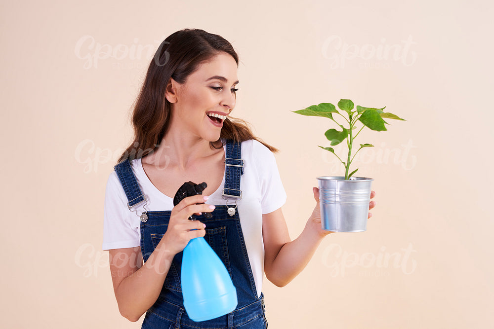 Happy woman spraying the plants with insecticide spray