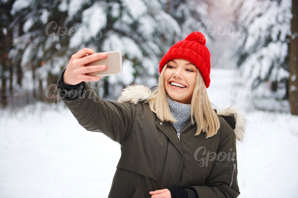 Smiling woman making selfie in winter forest