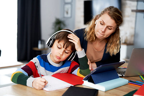 Mother working and helping her son with homework