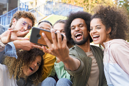 Group of happy young people doing selfie together outdoors