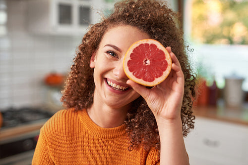 Portrait of woman covering her eye with grapefruit