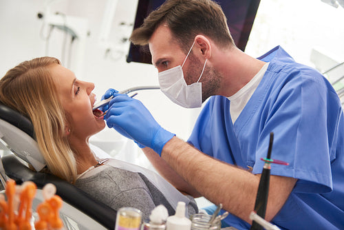 Focused stomatologist using dental drill and dental mirror
