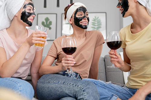 Women with carbon facial mask drinking wine