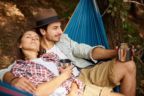 Couple in love relaxing on hammock in forest