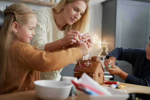 Image of family spending Christmas time on decorating gingerbread house