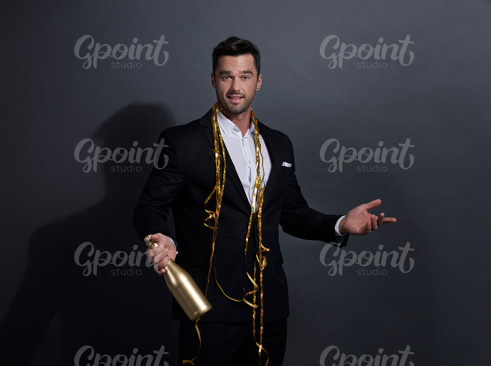 Man holding a bottle of champagne and pointing at copy space